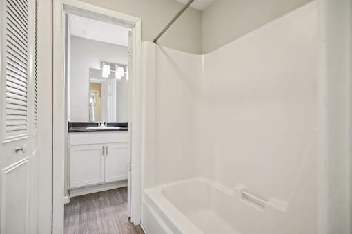 A white bathroom with a tub and a mirror.