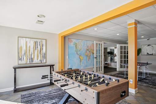 A foosball table is in the middle of a room with a world map on the wall.