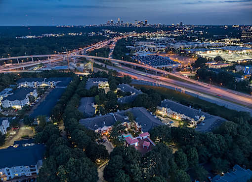 A nighttime aerial view of a city with a highway and buildings.