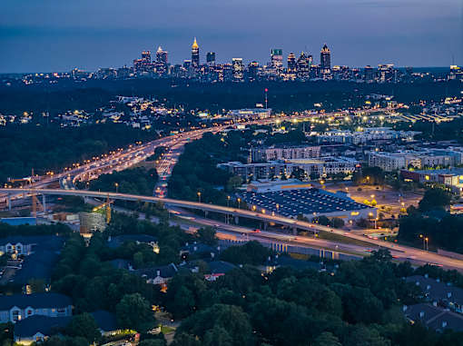 A cityscape at dusk with a highway running through it.