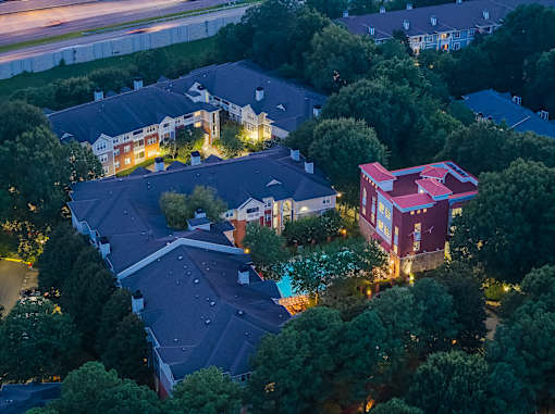 A red building with a white roof is surrounded by trees.
