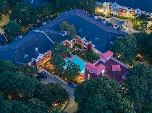 A nighttime aerial view of a residential area with houses and trees.