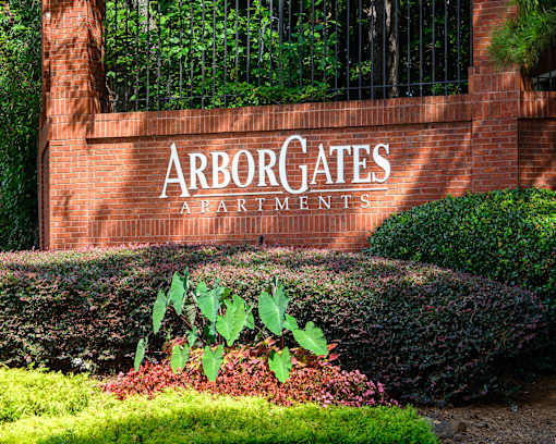 A sign that says Arborgates Apartments in front of a fence.