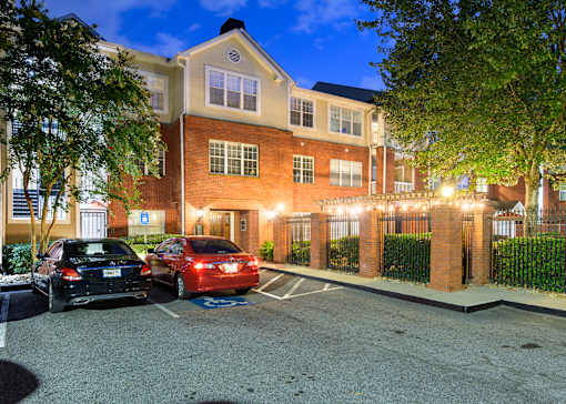 A parking lot with cars parked in front of a brick building at night.