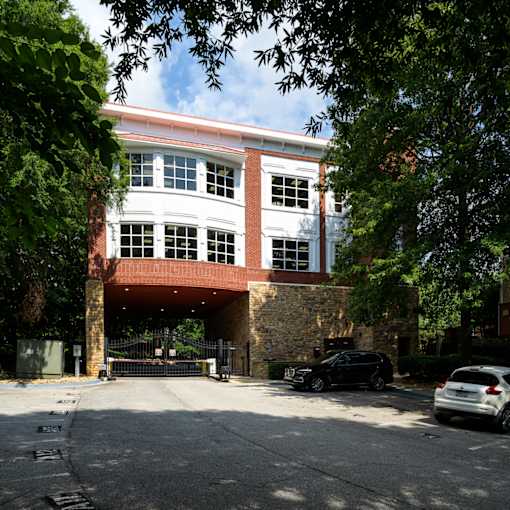 A car is parked in front of a building with a red brick archway.