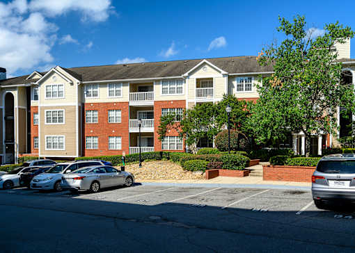 A parking lot in front of a multi-story apartment building.