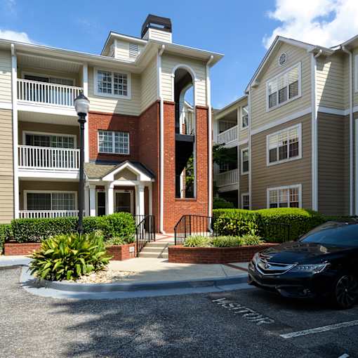 A black car is parked in a parking spot in front of a building.
