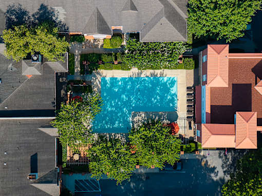 A swimming pool surrounded by trees and buildings.