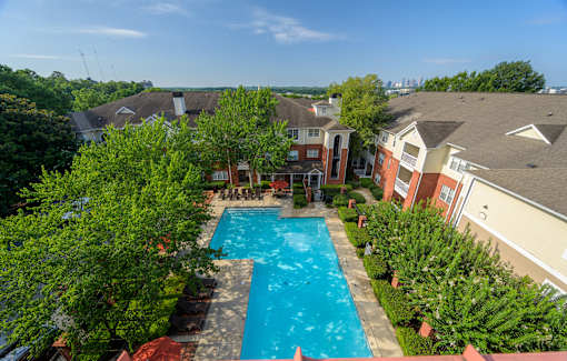 A swimming pool surrounded by trees and houses.
