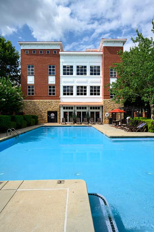 A swimming pool in front of a two-story building.
