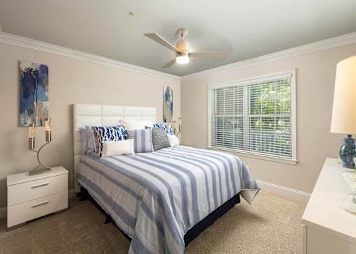 A bedroom with a bed, nightstands, and a ceiling fan.