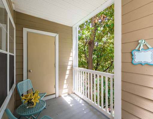 A chair with a yellow flower on it is on a porch.