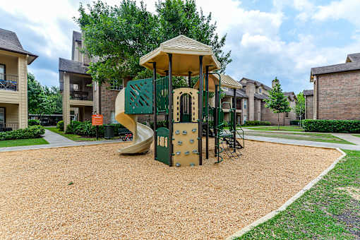 A playground with a green slide and a yellow canopy.