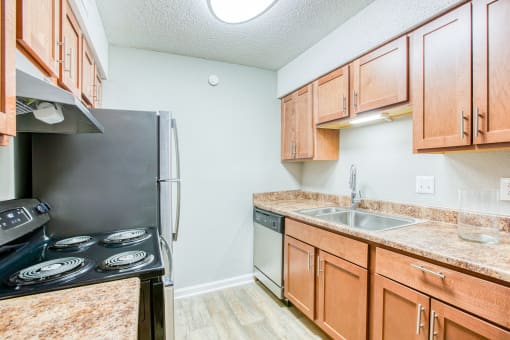 a kitchen with wood cabinets and a sink and a refrigerator at The Grove Brentwood, Tennessee, 37211