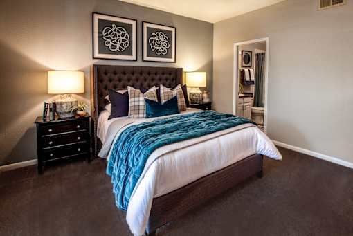 A bedroom with a large bed and two lamps.