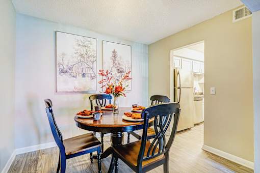 A dining room with a table set for two and two chairs.