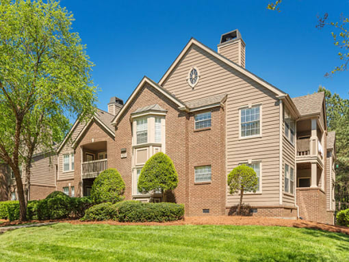 a brick apartment building with trees and grass at Radbourne Lake Apartments, Charlotte, 28269 ?