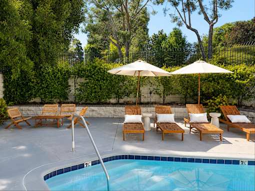 A pool with a diving board and lounge chairs.