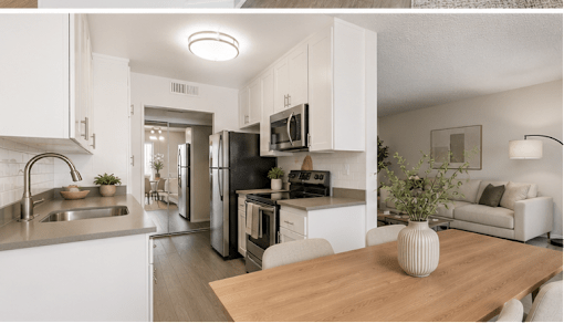 A modern kitchen with white cabinets and a wooden table.