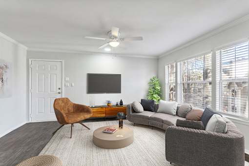 A living room with a brown chair, grey couch, and a flat screen TV mounted on the wall.