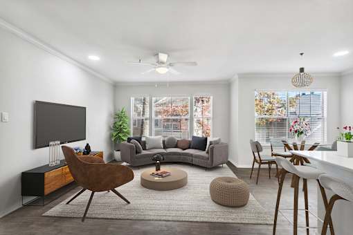 A living room with a grey couch, a brown chair, a white table, and a television.