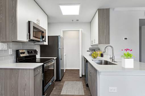 A modern kitchen with a refrigerator, microwave, oven, and sink.