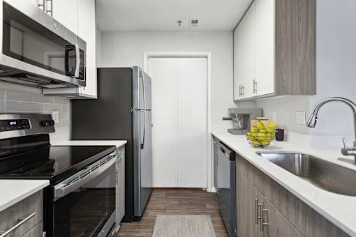A modern kitchen with black appliances and wooden cabinets.
