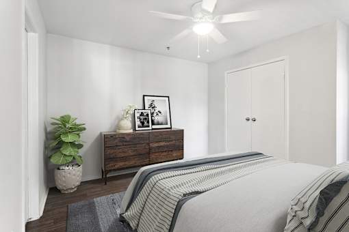 A bedroom with a bed, dresser, and ceiling fan.