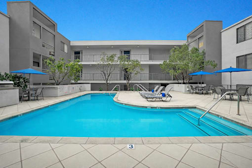 A swimming pool in front of a building with a blue sky.