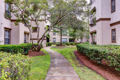 a sidewalk leading to an apartment building with trees and bushes at Stone Creek at Old Farm Apartments, Houston, 77063