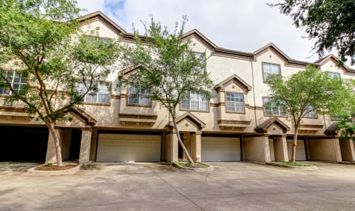 the front of a house with two garages and trees at Stone Creek at Old Farm Apartments, Houston, Texas