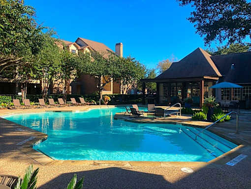A swimming pool surrounded by lounge chairs and trees.