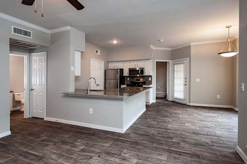 A spacious kitchen and living room with wood flooring and white walls.