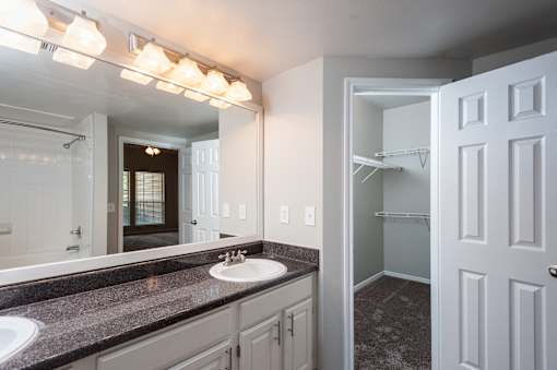 A bathroom with a sink, mirror, and lighting fixture.