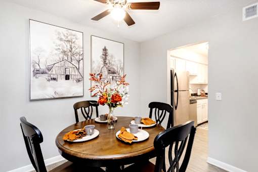 A dining room with a table set for two and a framed picture on the wall.
