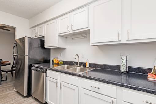 A kitchen with white cabinets and black countertops.