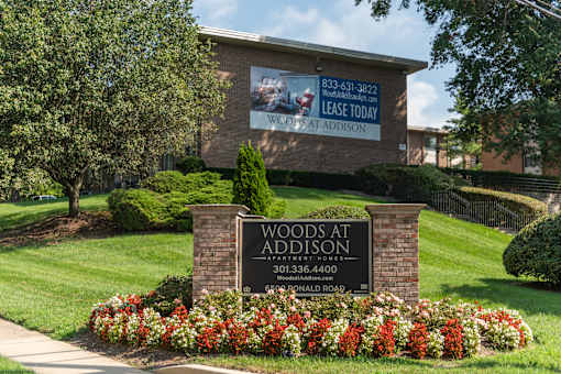 A sign for Woods at Addison with a phone number and a website.