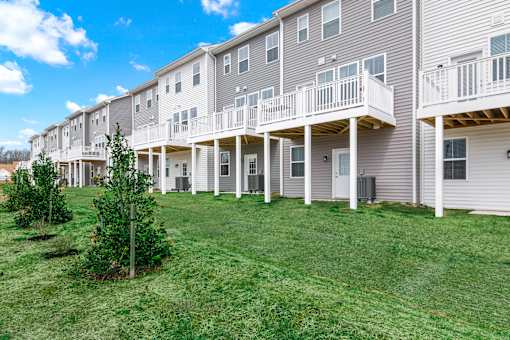 A row of townhouses with white balconies and grey siding.
