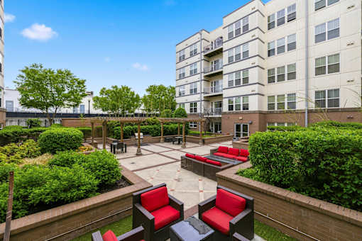 A courtyard with red and black chairs and a brick wall.