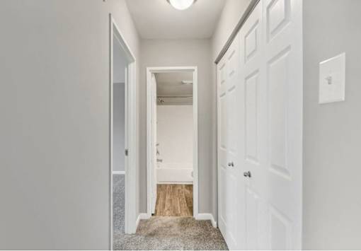 A hallway with a white door and a white wall.