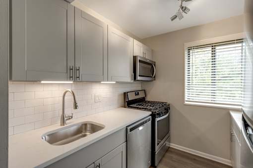 A kitchen with a stainless steel sink and a microwave above it.