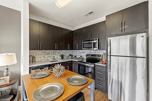 A modern kitchen with a wooden table and grey cabinets.