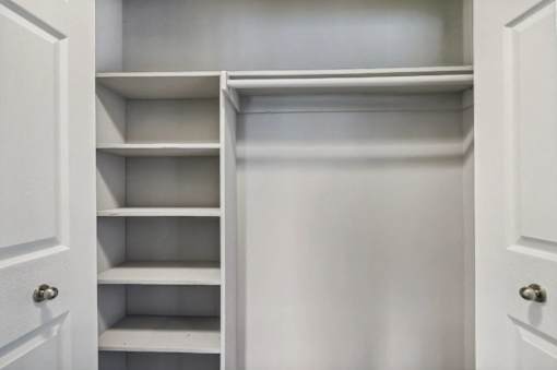 A white closet with shelves and doors.
