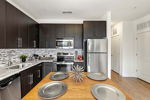 A modern kitchen with a wooden table and stainless steel appliances.
