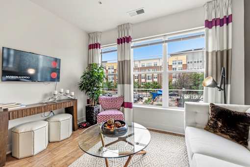 A living room with a white couch, a glass coffee table, and a flat-screen TV mounted on the wall.
