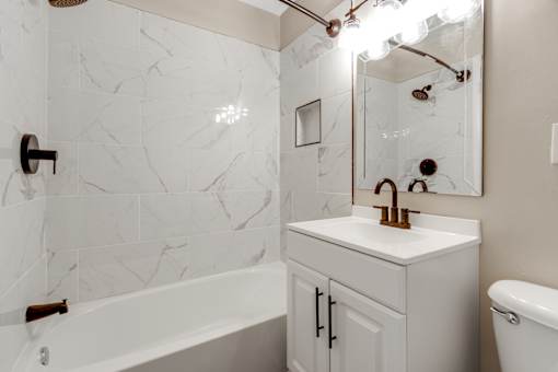 A white bathroom with a marble wall and a white sink.