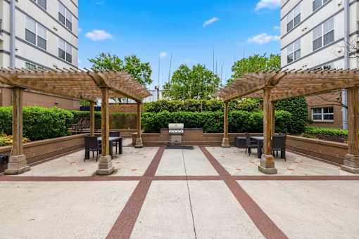 A courtyard with a fountain and benches under wooden pergolas.