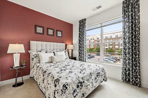 A bedroom with a large bed and a window overlooking a parking lot.