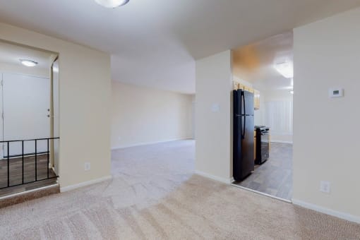 a renovated living room and kitchen with a black refrigerator