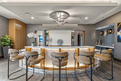 A modern bar area with a white counter and brown chairs.